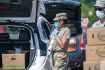 U.S. Army Pfc. Stephanie Huertas, a motor transport operator with the Delaware Army National Guard's 1049th Transportation Company, carries a stack of cans at a drive-thru food pantry on the grounds of Dover International Speedway in Dover, Delaware, June 24, 2020. Capt. Brendan Mackie